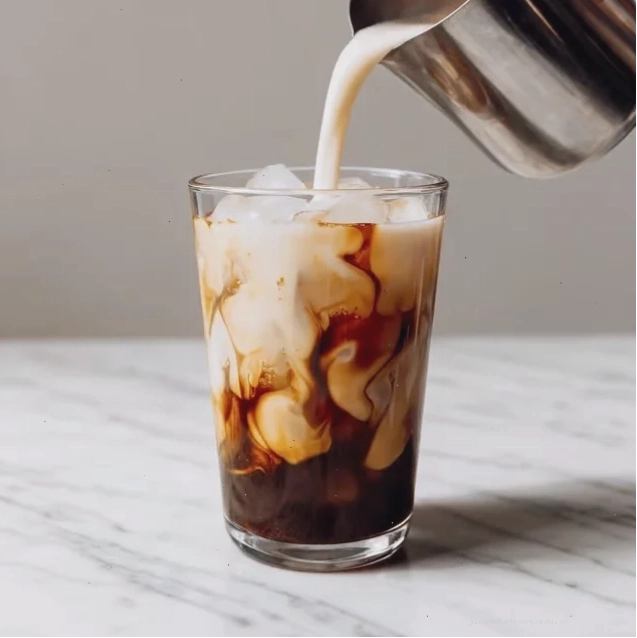 Espresso lắc đường nâu đá phân tầng trên lớp sữa trong ly thủy tinh cao với khói bốc lên nhẹ nhàng